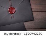 Black envelopes with wax seal on wooden background, flat lay