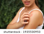 Woman scratching shoulder with...