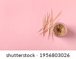 Wooden toothpicks and holder on pink background, flat lay. Space for text