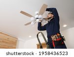Electrician repairing ceiling fan with lamps indoors. Space for text