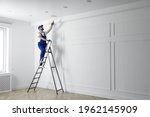 Handyman painting ceiling with white dye indoors, space for text
