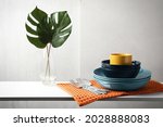 Set of clean dishware, cutlery and tropical leaves on white table