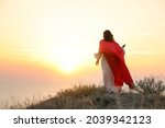 Jesus Christ on hills at sunset, back view. Space for text