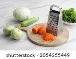 Grater and fresh vegetables on white marble table