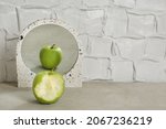 Bitten Green Apple Near Mirror...