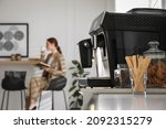 Small photo of Modern electric coffee machine on table in office. Space for text