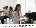 Woman preparing fresh aromatic coffee with modern machine in office