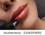Small photo of Young woman undergoing procedure of permanent lip makeup in tattoo salon, top view