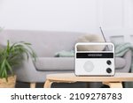 Stylish white radio on wooden table indoors. Space for text