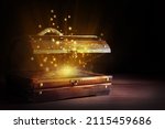 Small photo of Open treasure chest with gold coins on wooden table against black background