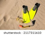 Pair of flippers, snorkel and diving mask on sandy beach, flat lay. Space for text