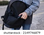 Man putting pepper spray into backpack outdoors, closeup