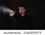 Man using pepper spray against black background, focus on hand