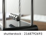 Small photo of Newton's cradle on wooden table, closeup. Physics law of energy conservation