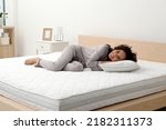 Happy young African American woman on bed with comfortable mattress and pillow at home