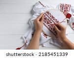Woman embroidering shirt with...