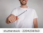 Happy worker holding screwdriver on white background, closeup