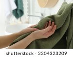 Woman wiping hands with towel in bathroom, closeup