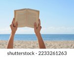 Woman reading book on beach...