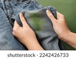 Woman holding jeans with stain...