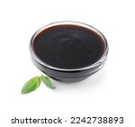 Glass bowl with balsamic glaze and basil leaves on white background
