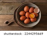 Bowl with raw chicken eggs on wooden table, top view