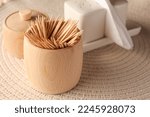 Wooden holder with many toothpicks on wicker mat, closeup. Space for text