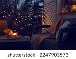 Small photo of Beautiful view of garden furniture with pillow, soft blanket and burning candles at balcony
