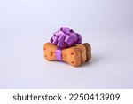 Small photo of Bone shaped dog cookies with purple bow on white background