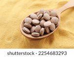 Wooden spoon of brewer`s yeast tablets on powder, closeup