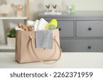 Mother's bag with baby's stuff on white wooden table indoors. Space for text