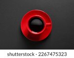 Red cup with aromatic coffee on black background, top view