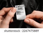 Woman holding clothing label on black garment, closeup