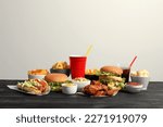 French fries, burgers and other fast food on wooden table against white background