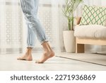 Barefoot woman walking on white parquet at home, closeup. Heated floor