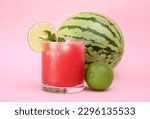 Glass of delicious watermelon drink with mint, lime and fresh fruits on pink background