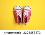 Cute baby shoes on yellow background, flat lay