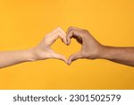 International relationships. People making heart with hands on orange background, closeup