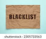 Small photo of Crumpled paper with word Blacklist on light blue background, top view