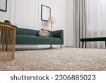 Stylish living room with soft beige carpet, coffee table and sofa, low angle view. Interior design