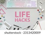 Words Life Hacks on white table, Workplace with computer keyboard and stationery, flat lay