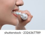 Woman brushing her teeth with electric toothbrush on white background, closeup. Space for text