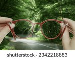 Small photo of Vision correction. Woman looking through glasses and seeing forest clearer