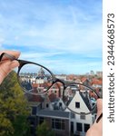 Small photo of Vision correction. Woman looking through glasses and seeing cityscape clearer