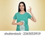 Happy woman with healthy digestive system on light yellow background. Illustration of gastrointestinal tract