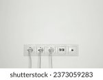 Small photo of Many power sockets with plugs, ethernet and TV coax plates on white wall indoors. Space for text