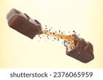 Broken chocolate bar with yummy caramel in air on beige background