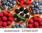 Tartlets with different fresh berries on light table, flat lay. Delicious dessert