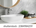 Small photo of Potted artificial plants, rolled towels and soap near sink on bathroom vanity