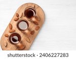 Shot glasses with tasty amaretto liqueur and almonds on white wooden table, top view. Space for text